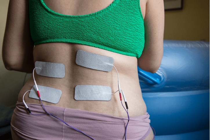 woman's back with four TENS machine pads covering lower back