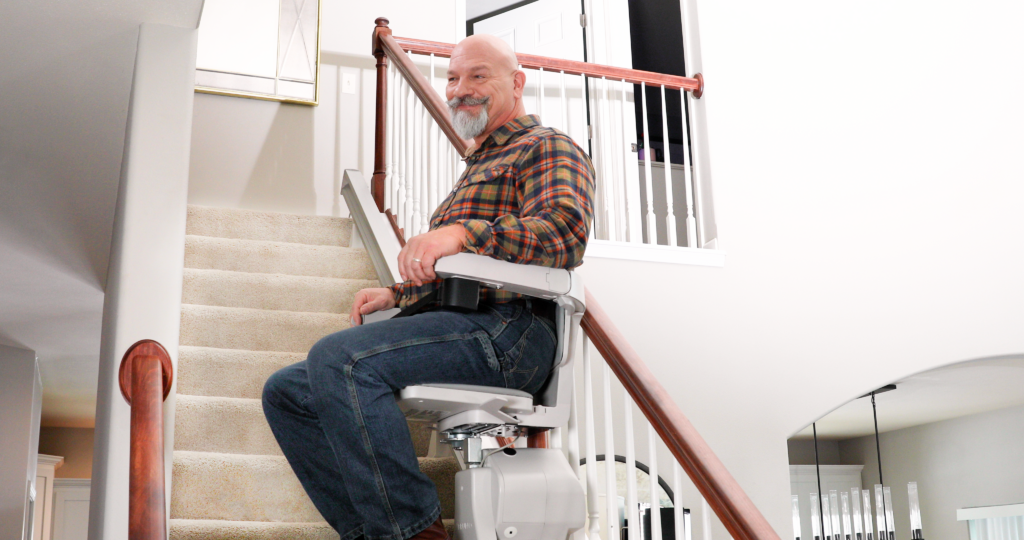 man riding a Bruno stairlift up stairs in a home